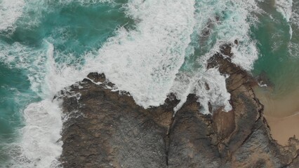 Crystal green waves crash against the stone coast of