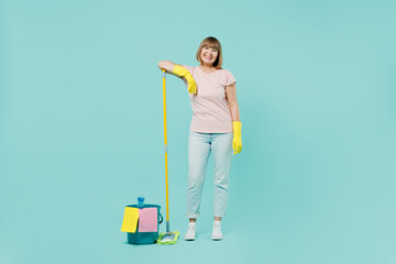Full body smiling elderly housewife woman 50s in pink t-shirt gloves doing housework hold mop and bucket isolated on plain pastel light blue background studio Housekeeping cleaning tidying up concept