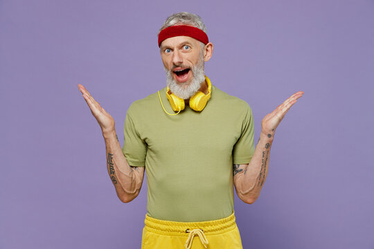 Fun elderly gray-haired bearded man 40s years old in headband khaki t-shirt spread hands isolated on plain pastel light purple background studio portrait. Workout sport motivation lifestyle concept