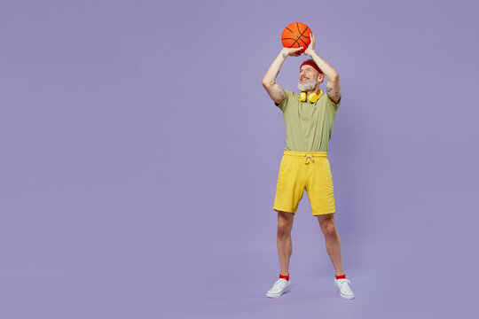 Full Size Body Length Sporty Fun Elderly Gray-haired Bearded Man 40s Years Old In Headband Khaki T-shirt Play Throw Basketball In Ring Isolated On Plain Pastel Light Purple Background Studio Portrait.