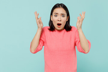Young shocked woman of Asian ethnicity 20s wearing pink sweater spread hands look camera with open mouth isolated on pastel plain light blue color background studio portrait. People lifestyle concept.
