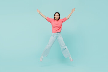 Fototapeta na wymiar Full body young smiling fun happy woman of Asian ethnicity 20s wearing pink sweater jumpo high with outstretched hands isolated on pastel plain light blue color background. People lifestyle concept.