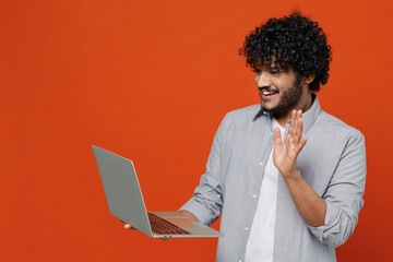 Fun young bearded Indian man 20s years old wear blue shirt get video call using laptop pc computer...