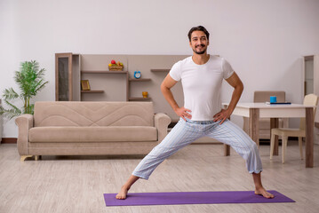 Fototapeta premium Young man doing sport exercises at home
