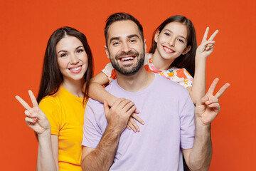 Young cheerful happy parents mom dad with child kid daughter teen girl in basic t-shirts showing...