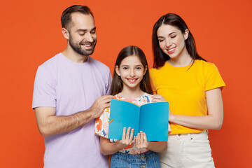 Young parents mom dad with child daughter teen girl wear basic t-shirts read book with kid help to...