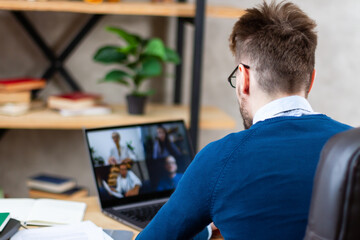 Successful confident top manager or coach, holding video conference online meeting with happy multiracial business colleagues, discussing working issues distantly at home office using computer app.