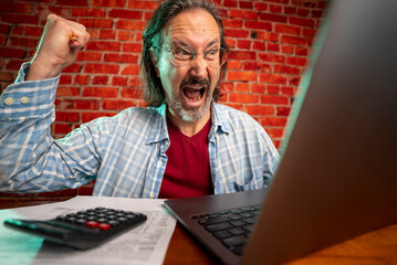 Funny portrait of angry crazy man doing tax prep to balance budget getting debt deficit finding mistake in calculations. Annoyed male count business costs on bankruptcy risk
