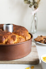 Easter cake with raisins in an aluminum shape on a wooden cutting board in the kitchen. Festive pastries for a family dinner. Homemade food concept. Vertical orientation.
