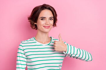 Portrait of attractive cheerful girl showing thumbup ad advert solution isolated over pink pastel color background