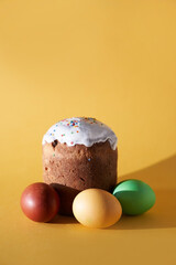 Close-up of colored Easter eggs and kulich on a yellow background. With a space to copy. High quality photo