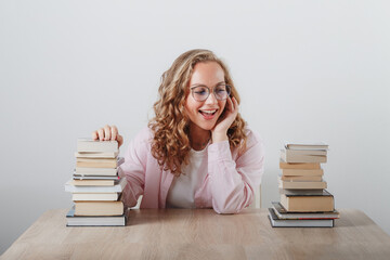 a girl looks at a large stack of books