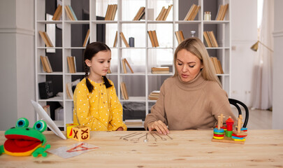 speech therapist a woman is engaged with a girl student with the help of speech therapy tools....