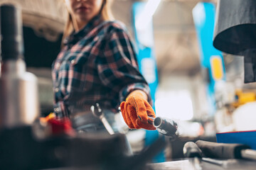 Female auto mechanic. beautiful young red-headed girl in working process at auto service station,...