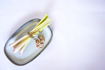Fresh lemongrass tied with a rope and slices on a blue ceramic plate.