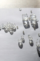 Various transparent beads on white background, illuminated by sunlight and reflectiing light. Selective focus.