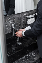 cropped view of man washing hands in modern bathroom in hotel