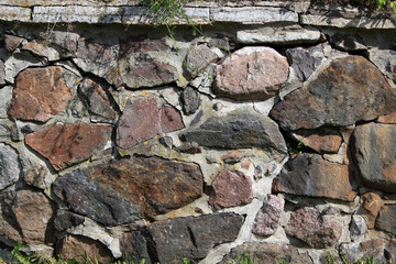 A close-up of a cobblestone wall. The background is made of colored stone.