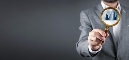 Man showing magnifying glass with graph. Business analyzing concept