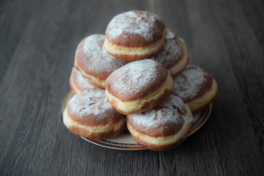 pączki z pudrem ułożone  na talerzyku stojącym na stole