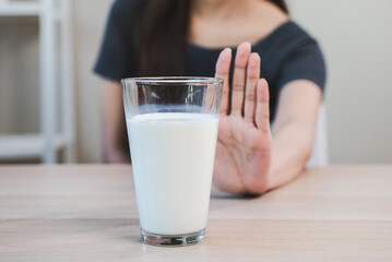 lactose intolerance concept. Woman pushing glass of milk deny to drink.