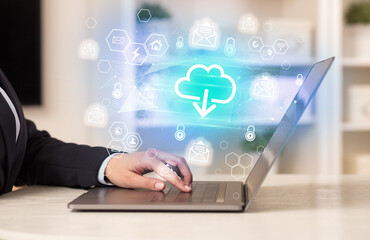 Hands working on laptop with digital icons