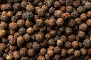 Allspice jamaica pepper texture background. Dried brown berries of the Pimenta dioica tree. Concepts of organic spices, seasonings and condiments for cooking and food design. Macro shot.