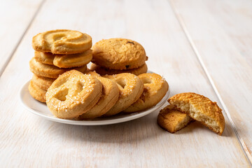 Tasty shortbread cookies with sugar on a saucer over white wooden table. Crispy butter biscuits for breakfast close-up. Baked pastry, sweet food, snack and dessert concepts.
