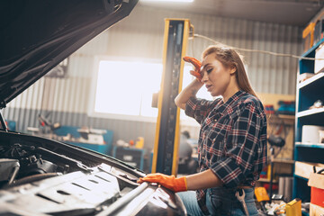 Destroying gender stereotypes. Young woman auto mechanic working at auto service station using different work tools. Gender equality. Work, occupation, car