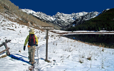 A winter hiker heads past Piney Lake into Colorado's Eagle's Nest Wilderness near Vail, with the Gore Range in the background.