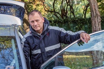 portrait of a handsome middle-aged european man 50-55 years old standing near the car