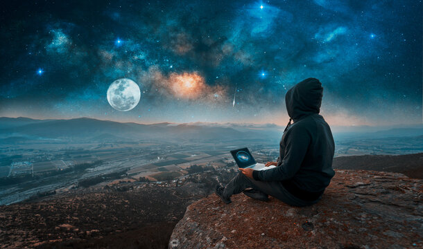 digital nomad sitting on the top of the mountain with a laptop at night