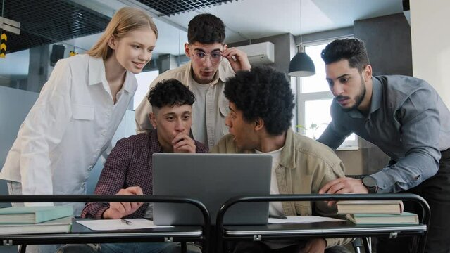 Young excited happy businesspeople team in office looking at laptop screen reading good news group corporate employees people celebrating professional victory success triumph great teamwork result