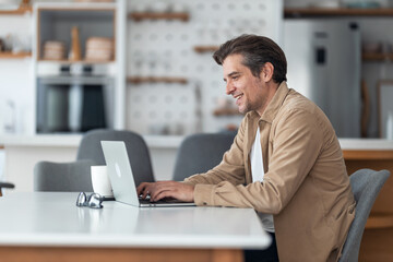Fototapeta premium Happy male freelancer surfing the Internet on a computer from home.