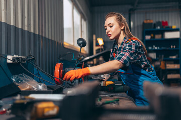 Female auto mechanic. beautiful young red-headed girl in working process at auto service station,...