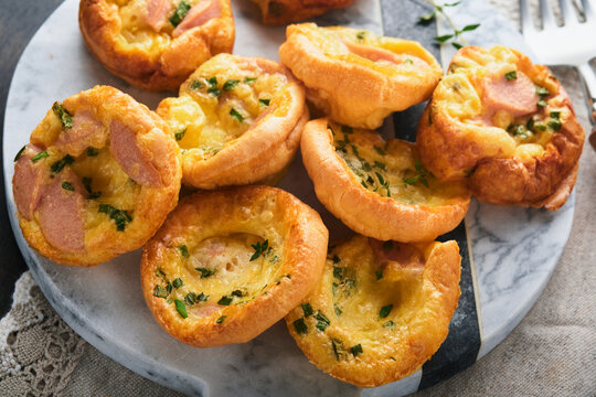 Delicious egg muffins with green onions, bacon, cheese and tomatoes on wooden board on old wooden rustic background. Healthy high protein and low carb breakfast. Homemade food.
