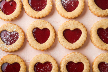 Traditional Linzer cookie with strawberry jam and powder sugar on pink beautiful background. Top view. Traditional homemade Austrian sweet dessert food on Valentines Day. Holiday snack concept.