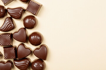 Chocolate pralines assortment on beige background, flat lay, top view with copy space