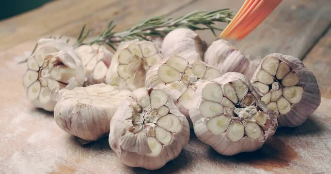 Cutting board with chopped garlic and rosemary sprig. Garlic is smeared with olive oil