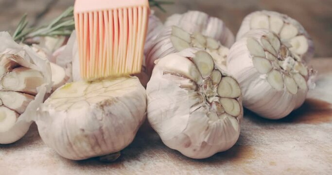 The garlic is smeared with olive oil before roasting. Preparing appetizers. Still life with rotation