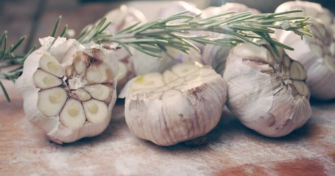 Sliced garlic and a sprig of rosemary on a board in bright light