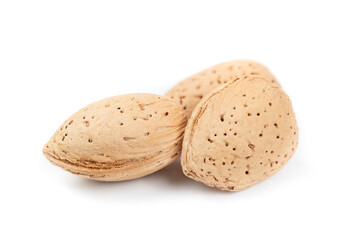 Isolated shelled almonds, close up. Group of almond nuts in yellow oval shell, protecting fatty acids and vitamins from temperature change. High calorie superfood for a heathy diet. Selective focus.