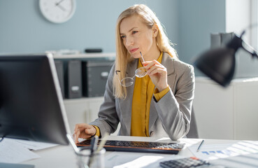 Confident caucasian business woman in formal suit typing on modern pc while working at office....