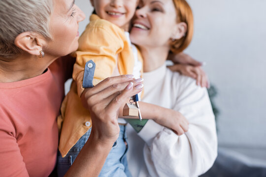 Woman Holding Key From New Apartment Near Happy Lesbian Girlfriend And Adopted Girl