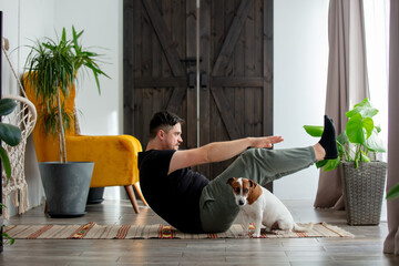 man trying to do sports exercises next to a dog at home on the floor