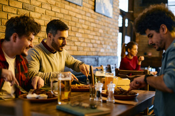 Fototapeta na wymiar Young man and his male friends eat while gathering for lunch in a pub.