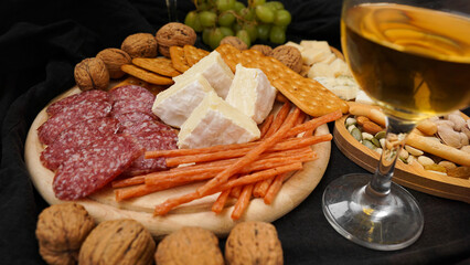 Cheese platter with assorted cheeses, grapes, nuts over black background. Italian cheese platter for wine.