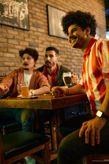 Multiracial group of sports fans watching match on TV in a pub.