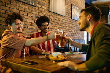 Happy Lebanese man and his male friends celebrate and toast with beer after watching sports game in a bar.