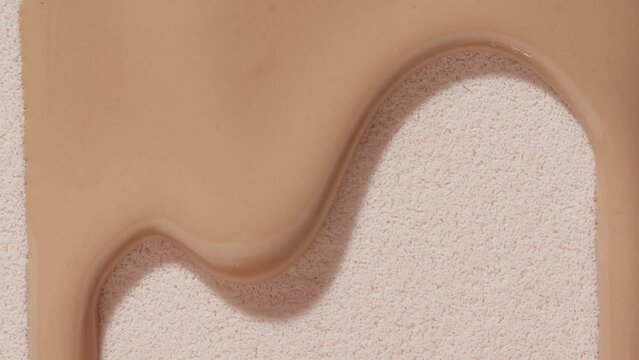 Foundation for face, smear, concealer, cosmetic liquid foundation, or cream beige color smudge flowing down on sponge. Beauty skincare sample. Macro Shot. Close up. High quality 4k footage